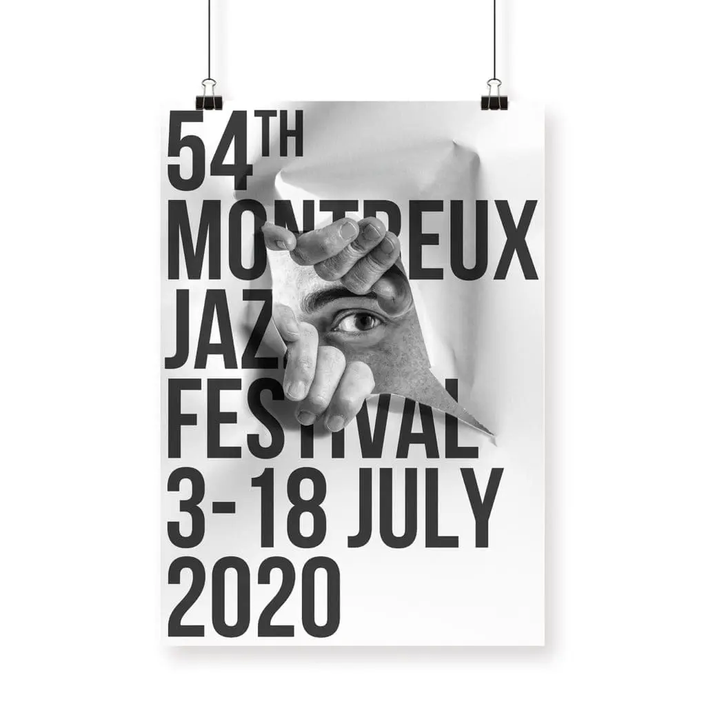 Poster JR, 2020: Bold black text over an image of a hand tearing paper to reveal an eye. Created for the 54th Montreux Jazz Festival (3–18 July 2020), the poster hangs by two clips.