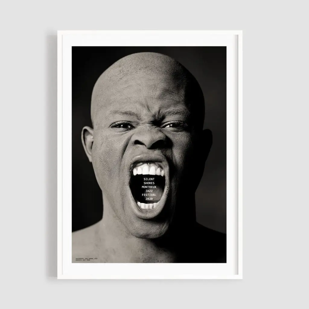 Une personne chauve criant sur un fond sombre avec "SILENCE IS NOT NECESSARILY PEACE" dans la bouche. "Affiche Silent Shores" de Greg Gorman, photo en noir et blanc, présentée dans un cadre blanc.