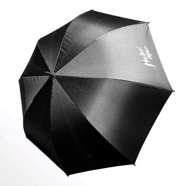 Grand parapluie noir Grand Parapluie Montreux Jazz Festival avec une finition légèrement brillante et le logo Moschino Fashion en blanc sur l'un des panneaux, sur un fond blanc uni.
