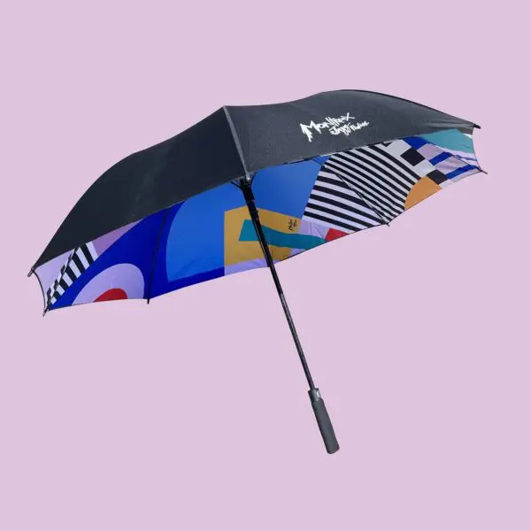 The Big Umbrella Camille Walala features a vibrant, Walala-inspired geometric-patterned underside and the Montreux Jazz Festival logo on top, shown against a plain light purple background.