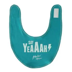 The Baby Bib Say Yeaaah! is teal with white "SAY YeAAAh" text, a small lightning bolt, and "Montreux Jazz Festival" in script at the bottom. It features a convenient Velcro closure at the top.