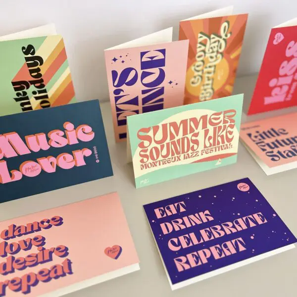 The Dance Love Desire Repeat Card features bold, retro-style typography and vibrant colors, displayed both upright and flat. The card showcases phrases like “Music Lover,” “Dance Love Desire,” and “EAT DRINK CELEBRATE REPEAT.”.