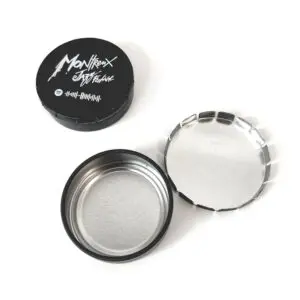 Un récipient rond en métal noir avec Montreux JMTF et un code Spotify sur le couvercle, montré ouvert à côté du couvercle et d'un sceau métallique intérieur.