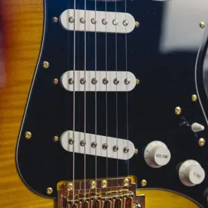 Close-up of the Atlanta from the Guitar Collection Limited Series, showing strings, three single-coil pickups, volume and tone knobs, a golden bridge on a sunburst body, and a black pickguard.