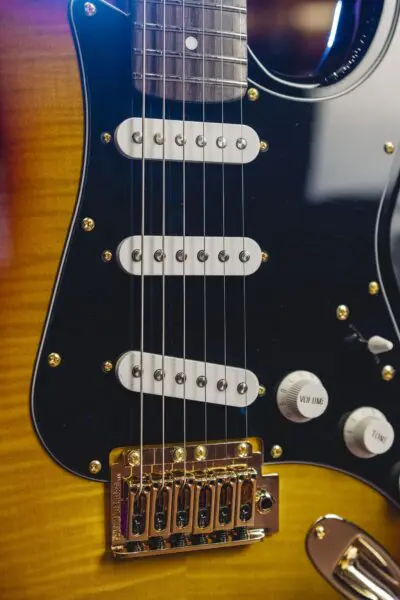 Close-up of the Atlanta from the Guitar Collection Limited Series, showing strings, three single-coil pickups, volume and tone knobs, a golden bridge on a sunburst body, and a black pickguard.