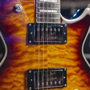 Gros plan d'une guitare électrique avec une finition sunburst ambre matelassée, un accastillage chromé, deux micros humbucker et un seul bouton de contrôle ambre visible.