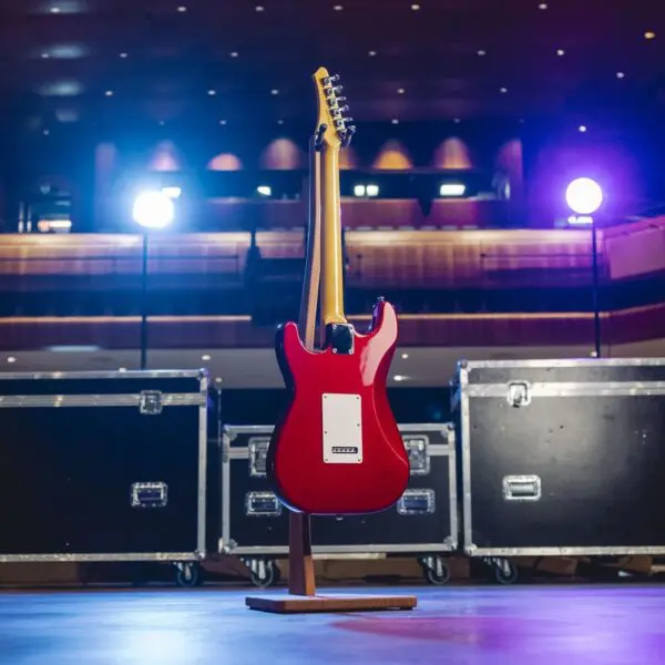 A São Paulo Guitar from the Limited Series, viewed from the back on a stand under stage lights, is positioned among equipment cases, evoking a concert atmosphere.