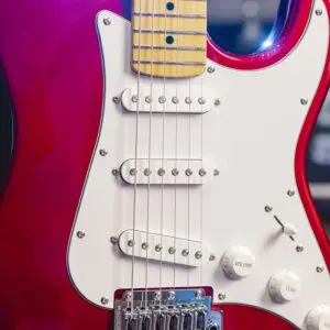 Close-up of the São Paulo from the Guitar Collection Limited Series: a red electric guitar with a white pickguard, three white pickups, control knobs, and part of a maple fretboard visible.