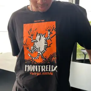 Someone wears a black T-Shirt Tomi Ungerer, 1993, with an orange and white cat playing piano keys and the text “Montreux XXVII Jazz Festival” and “July 2-17 1993.” The softly blurred background highlights the shirt design.