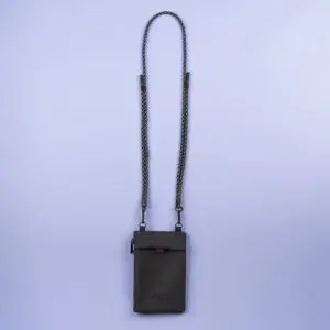 A dark gray, rectangular Festival Bag, Lakeside crossbody features a long, thin, detachable black-and-white braided strap, shown against a plain light purple background.