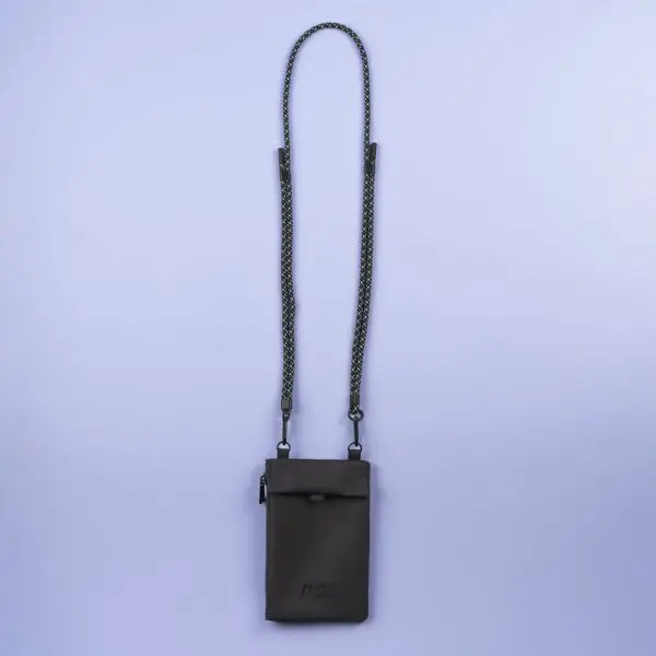 A dark gray, rectangular Festival Bag, Lakeside crossbody features a long, thin, detachable black-and-white braided strap, shown against a plain light purple background.