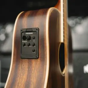 A close-up of the Miami Electro Acoustic Guitar Limited Serie’s side, showing its built-in Fishman Presys preamp with knobs for volume, bass, middle, and treble. The guitar has a natural wood finish.
