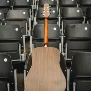 A Miami Electro acoustic guitar, Limited Serie, stands upright with its back to the camera amid rows of empty black stadium seats.