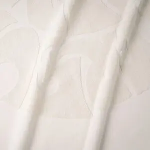 A close-up of the Beach Towel Coral, Vintage shows off-white fabric with a raised, abstract texture in curved shapes reminiscent of coral, gently draped to create soft folds and subtle shadows.