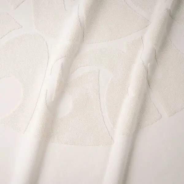 A close-up of the Beach Towel Coral, Vintage shows off-white fabric with a raised, abstract texture in curved shapes reminiscent of coral, gently draped to create soft folds and subtle shadows.