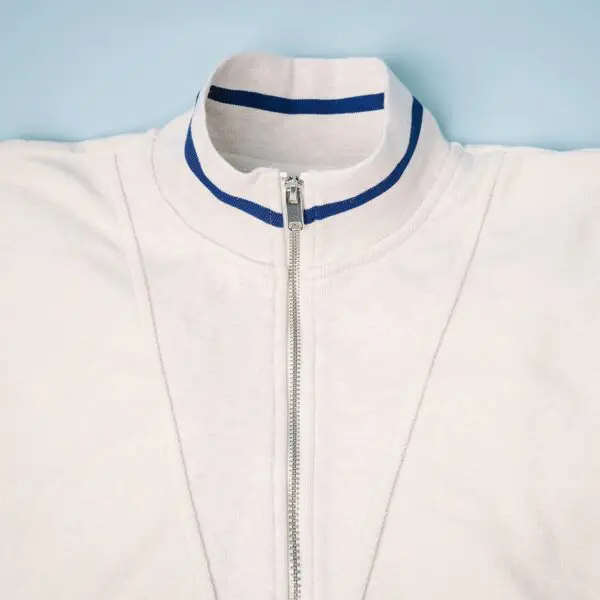 A close-up of the Sweat Unisex Terry Cloth Zip-Up Trucker Collar, Vintage, featuring two blue stripes, laid flat on a light blue background.