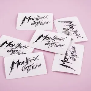 Six White Sticker Montreux Jazz Festival cards, featuring Rylsee’s stylized black lettering, are scattered on a pink surface.