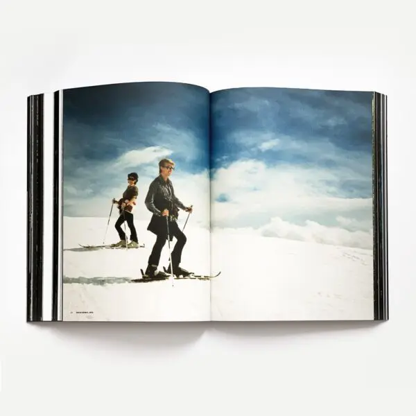 An open copy of "50 Summers Of Music" features a photo of two skiers in winter clothing gliding down a snowy slope beneath a bright blue sky with white clouds.