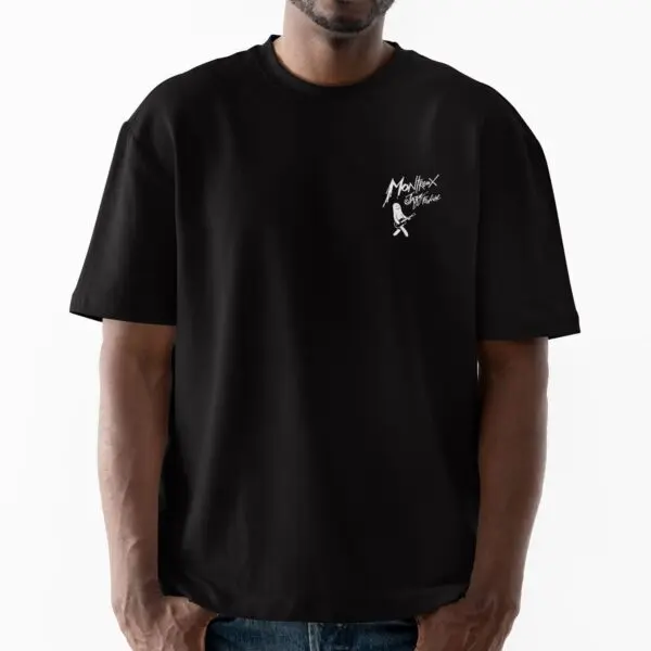 A man wears the loose-fitting black T-Shirt Lineup 2024, Limited Edition, featuring a small white graphic and "Montreux Jazz Festival" text on the left chest. He stands against a plain white background, showcasing festival spirit.