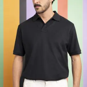A man in a black Polo Shirt pima cotton Montreux Jazz and white pants stands before a colorful striped background, his mustached face partially visible as he glances to the side.