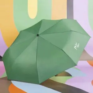 Un parapluie Parapluie vert avec un texte en blanc est ouvert et placé sur un fond abstrait et coloré avec des formes courbes en orange, vert, jaune et violet.