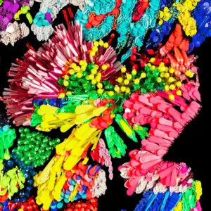 Un collage abstrait vibrant inspiré par Affiche Kévin Germanier, 2026, regroupe des objets en plastique colorés sur un fond noir, formant des motifs dynamiques dans des teintes rouges, jaunes, vertes, bleues et roses.