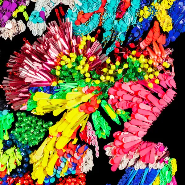 Un collage abstrait vibrant inspiré par Affiche Kévin Germanier, 2026, regroupe des objets en plastique colorés sur un fond noir, formant des motifs dynamiques dans des teintes rouges, jaunes, vertes, bleues et roses.